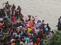 Bangladeshi Hindu devotees carry an idol of the Hindu Goddess Durga to immerse in the Buriganga River during the final day of the Durga Puja...