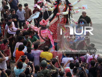 Bangladeshi Hindu devotees carry an idol of the Hindu Goddess Durga to immerse in the Buriganga River during the final day of the Durga Puja...