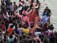 Bangladeshi Hindu devotees carry an idol of the Hindu Goddess Durga to immerse in the Buriganga River during the final day of the Durga Puja...