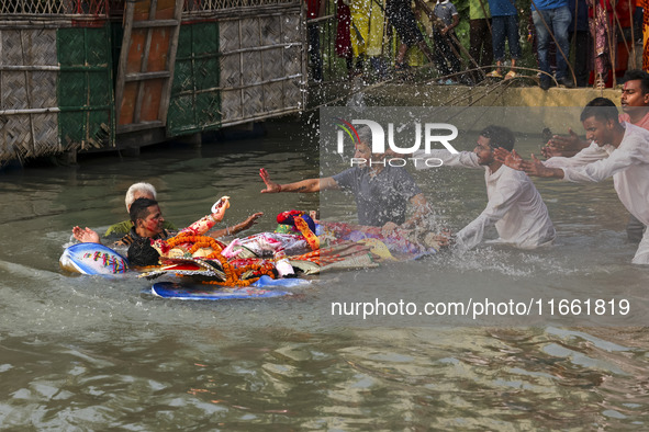 Bangladeshi Hindu devotees immerse an idol of their deity Durga into the Buriganga River during celebrations on the last day of the Durga Pu...