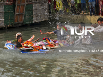 Bangladeshi Hindu devotees immerse an idol of their deity Durga into the Buriganga River during celebrations on the last day of the Durga Pu...