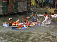 Bangladeshi Hindu devotees immerse an idol of their deity Durga into the Buriganga River during celebrations on the last day of the Durga Pu...