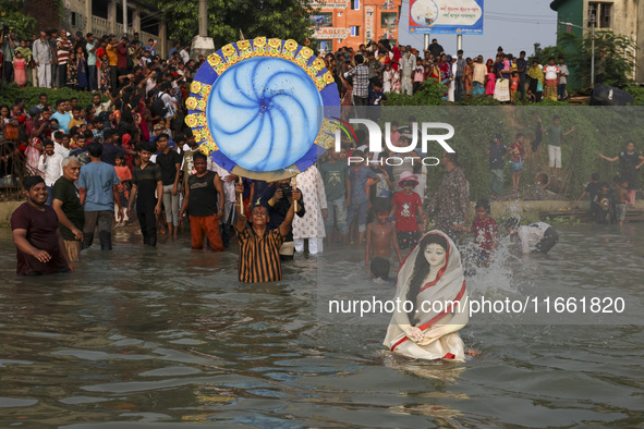 Bangladeshi Hindu devotees immerse an idol of their deity Durga into the Buriganga River during celebrations on the last day of the Durga Pu...