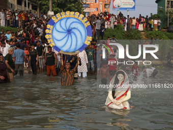 Bangladeshi Hindu devotees immerse an idol of their deity Durga into the Buriganga River during celebrations on the last day of the Durga Pu...