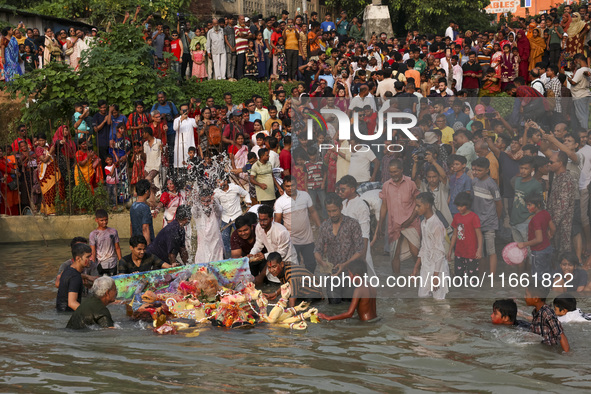 Bangladeshi Hindu devotees immerse an idol of their deity Durga into the Buriganga River during celebrations on the last day of the Durga Pu...