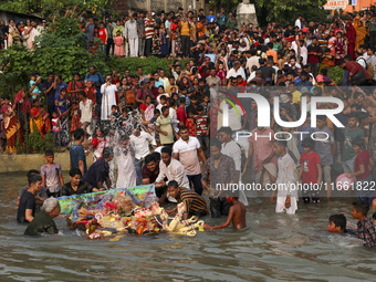 Bangladeshi Hindu devotees immerse an idol of their deity Durga into the Buriganga River during celebrations on the last day of the Durga Pu...