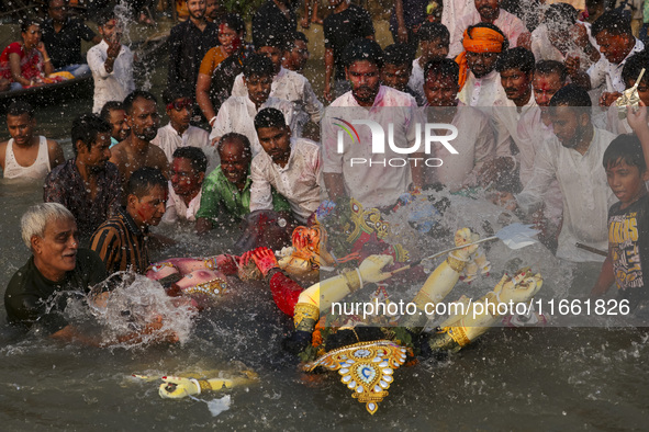 Bangladeshi Hindu devotees immerse an idol of their deity Durga into the Buriganga River during celebrations on the last day of the Durga Pu...