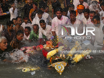 Bangladeshi Hindu devotees immerse an idol of their deity Durga into the Buriganga River during celebrations on the last day of the Durga Pu...