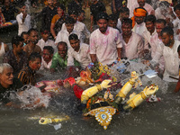 Bangladeshi Hindu devotees immerse an idol of their deity Durga into the Buriganga River during celebrations on the last day of the Durga Pu...