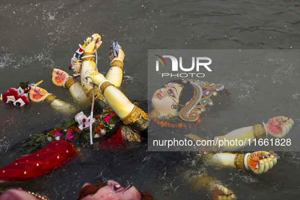 Bangladeshi Hindu devotees immerse an idol of their deity Durga into the Buriganga River during celebrations on the last day of the Durga Pu...