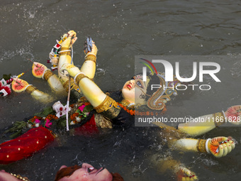 Bangladeshi Hindu devotees immerse an idol of their deity Durga into the Buriganga River during celebrations on the last day of the Durga Pu...