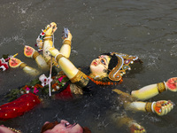 Bangladeshi Hindu devotees immerse an idol of their deity Durga into the Buriganga River during celebrations on the last day of the Durga Pu...