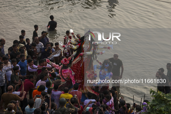 Bangladeshi Hindu devotees immerse an idol of their deity Durga into the Buriganga River during celebrations on the last day of the Durga Pu...