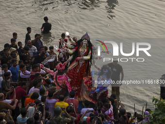 Bangladeshi Hindu devotees immerse an idol of their deity Durga into the Buriganga River during celebrations on the last day of the Durga Pu...