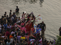 Bangladeshi Hindu devotees immerse an idol of their deity Durga into the Buriganga River during celebrations on the last day of the Durga Pu...