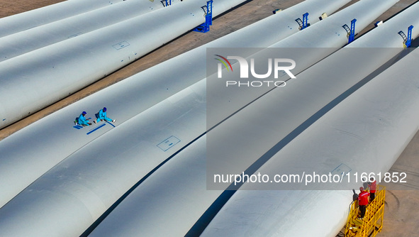 Technicians carry out strict testing of wind turbine blades before they leave the factory in the storage field of the wind turbine blade pro...