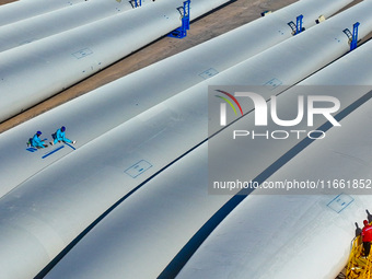 Technicians carry out strict testing of wind turbine blades before they leave the factory in the storage field of the wind turbine blade pro...