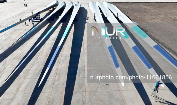 Technicians carry out strict testing of wind turbine blades before they leave the factory in the storage field of the wind turbine blade pro...