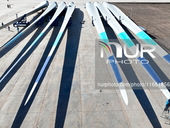 Technicians carry out strict testing of wind turbine blades before they leave the factory in the storage field of the wind turbine blade pro...