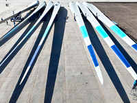 Technicians carry out strict testing of wind turbine blades before they leave the factory in the storage field of the wind turbine blade pro...