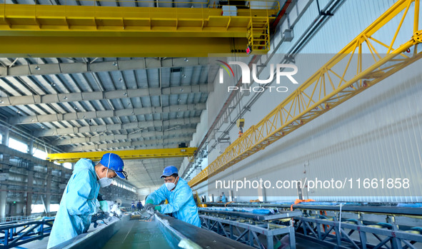 Staff produce wind turbine blades on the Shanghai Electric Wind Power (Zhangye) wind turbine blade production line in Zhangye City, Gansu Pr...