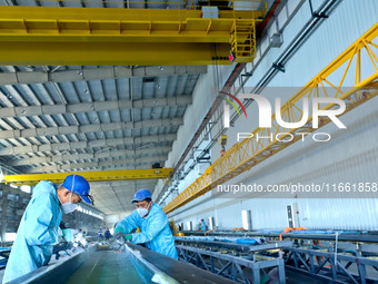 Staff produce wind turbine blades on the Shanghai Electric Wind Power (Zhangye) wind turbine blade production line in Zhangye City, Gansu Pr...