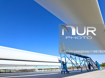 Technicians carry out strict testing of wind turbine blades before they leave the factory in the storage field of the wind turbine blade pro...