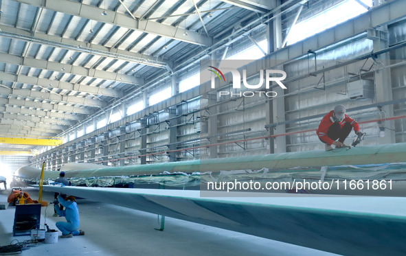 Staff produce wind turbine blades on the Shanghai Electric Wind Power (Zhangye) wind turbine blade production line in Zhangye City, Gansu Pr...