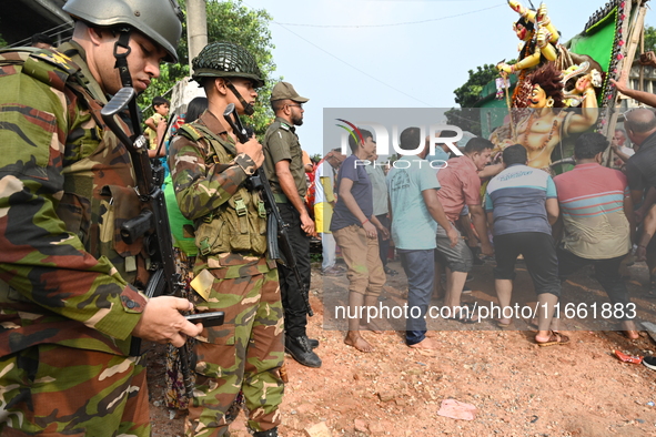 Bangladeshi Army soldiers escort Hindu devotees as they immerse an idol of the Hindu Goddess Durga into the river Buriganga in Dhaka, Bangla...