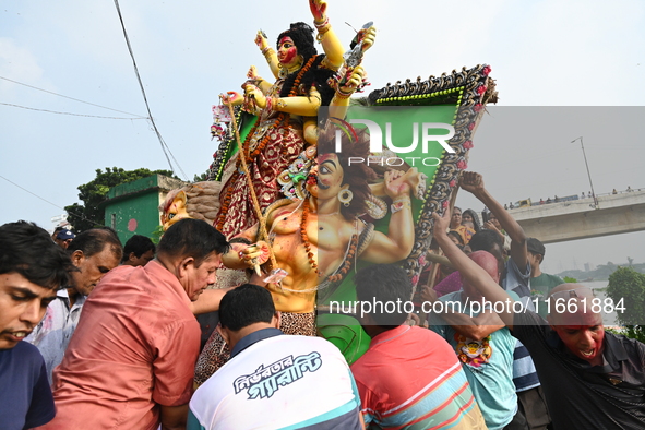 Bangladeshi Hindu devotees immerse an idol of the Hindu Goddess Durga into the river Buriganga in Dhaka, Bangladesh, on October 13, 2024. Th...