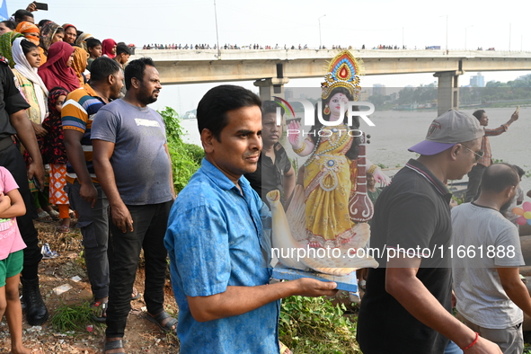 Bangladeshi Hindu devotees immerse an idol of the Hindu Goddess Durga into the river Buriganga in Dhaka, Bangladesh, on October 13, 2024. Th...