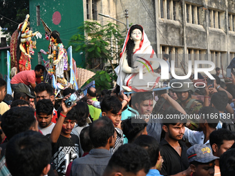 Bangladeshi Hindu devotees immerse an idol of the Hindu Goddess Durga into the river Buriganga in Dhaka, Bangladesh, on October 13, 2024. Th...