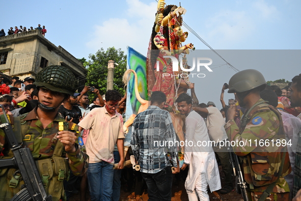 Bangladeshi Army soldiers escort Hindu devotees as they immerse an idol of the Hindu Goddess Durga into the river Buriganga in Dhaka, Bangla...