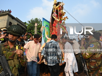 Bangladeshi Army soldiers escort Hindu devotees as they immerse an idol of the Hindu Goddess Durga into the river Buriganga in Dhaka, Bangla...