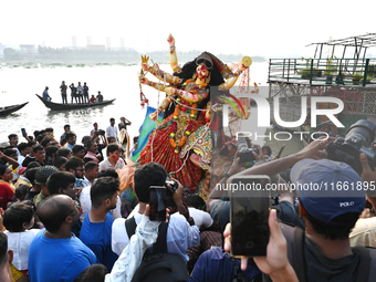 Bangladeshi Hindu devotees immerse an idol of the Hindu Goddess Durga into the river Buriganga in Dhaka, Bangladesh, on October 13, 2024. Th...