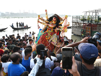 Bangladeshi Hindu devotees immerse an idol of the Hindu Goddess Durga into the river Buriganga in Dhaka, Bangladesh, on October 13, 2024. Th...