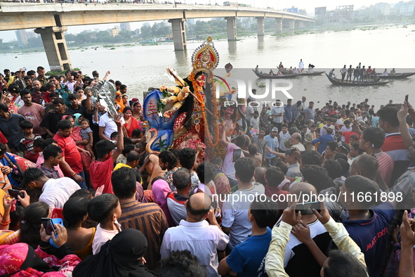 Bangladeshi Hindu devotees immerse an idol of the Hindu Goddess Durga into the river Buriganga in Dhaka, Bangladesh, on October 13, 2024. Th...