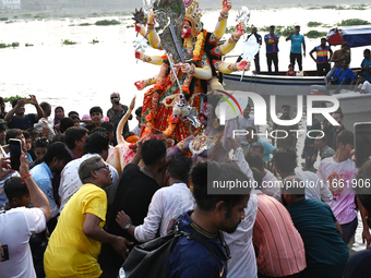 Bangladeshi Hindu devotees immerse an idol of the Hindu Goddess Durga into the river Buriganga in Dhaka, Bangladesh, on October 13, 2024. Th...