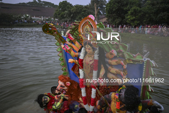 Bangladeshi Hindu devotees immerse an idol of their deity Durga in the pond during the final day (Vijaya Dashami) of the Durga Puja festival...