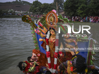 Bangladeshi Hindu devotees immerse an idol of their deity Durga in the pond during the final day (Vijaya Dashami) of the Durga Puja festival...