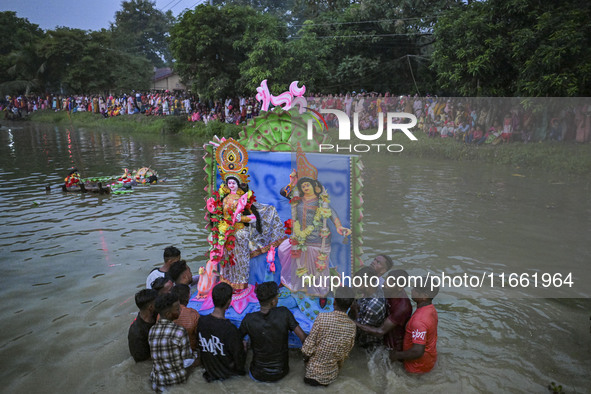 Bangladeshi Hindu devotees immerse an idol of their deity Durga in the pond during the final day (Vijaya Dashami) of the Durga Puja festival...