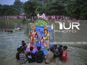 Bangladeshi Hindu devotees immerse an idol of their deity Durga in the pond during the final day (Vijaya Dashami) of the Durga Puja festival...