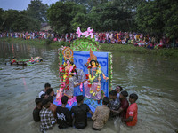 Bangladeshi Hindu devotees immerse an idol of their deity Durga in the pond during the final day (Vijaya Dashami) of the Durga Puja festival...