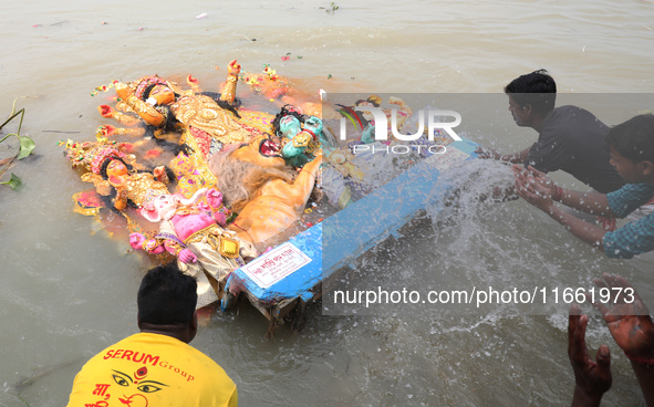 Devotees immerse an idol of the Hindu goddess Durga into the Hooghly River in Kolkata, India, on October 13, 2024. The annual Durga Puja fes...