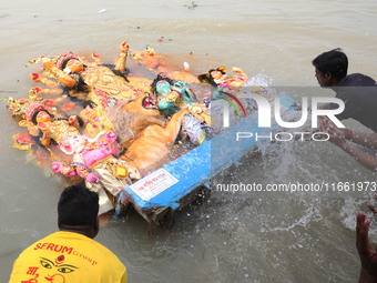 Devotees immerse an idol of the Hindu goddess Durga into the Hooghly River in Kolkata, India, on October 13, 2024. The annual Durga Puja fes...