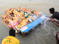 Devotees immerse an idol of the Hindu goddess Durga into the Hooghly River in Kolkata, India, on October 13, 2024. The annual Durga Puja fes...