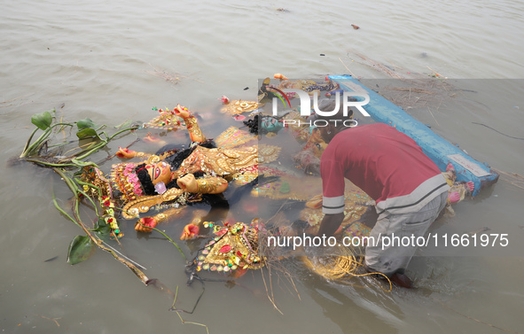 A devotee immerses an idol of the Hindu goddess Durga into the Hooghly River in Kolkata, India, on October 13, 2024. The annual Durga Puja f...