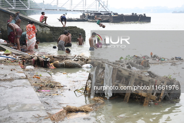 People bathe in the polluted water after the Hindu goddess Durga is immersed in the Hooghly River in Kolkata, India, on October 13, 2024. Th...