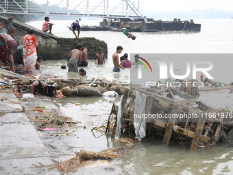 People bathe in the polluted water after the Hindu goddess Durga is immersed in the Hooghly River in Kolkata, India, on October 13, 2024. Th...