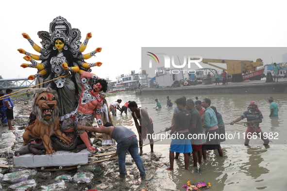 Devotees prepare an idol of the Hindu goddess Durga for its immersion into the Hooghly River in Kolkata, India, on October 13, 2024. The ann...